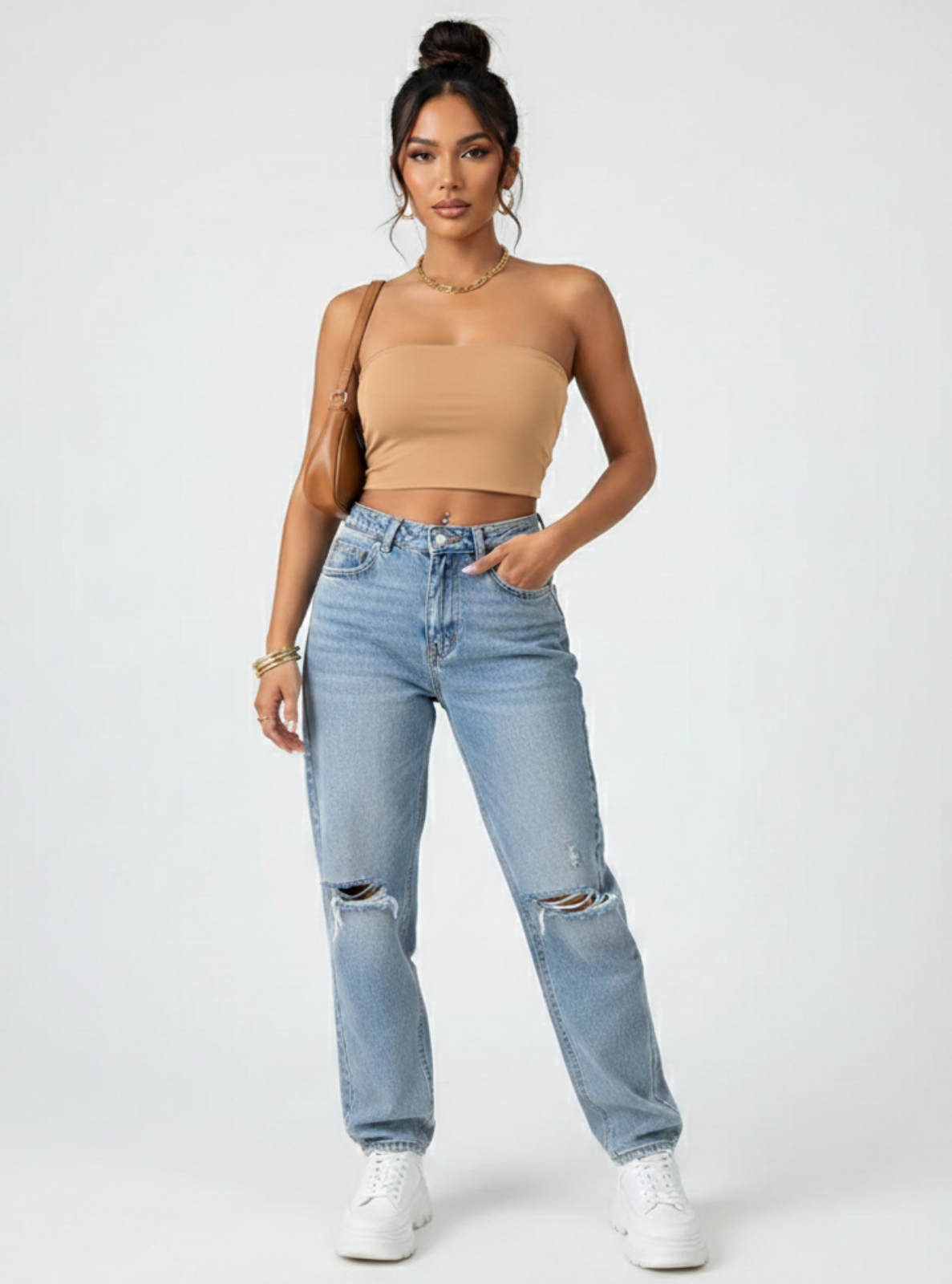 Woman wearing a beige crop top and light blue jeans on a white background