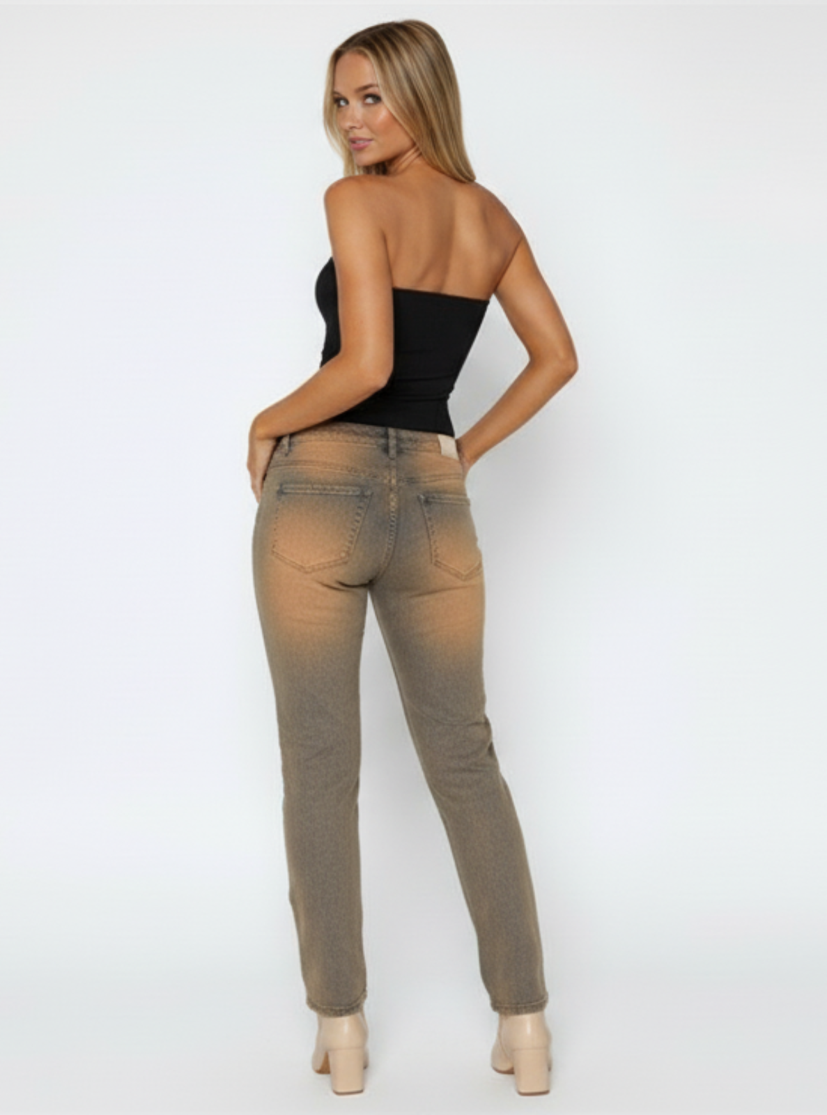 Woman wearing a black strapless top and beige jeans on a white background