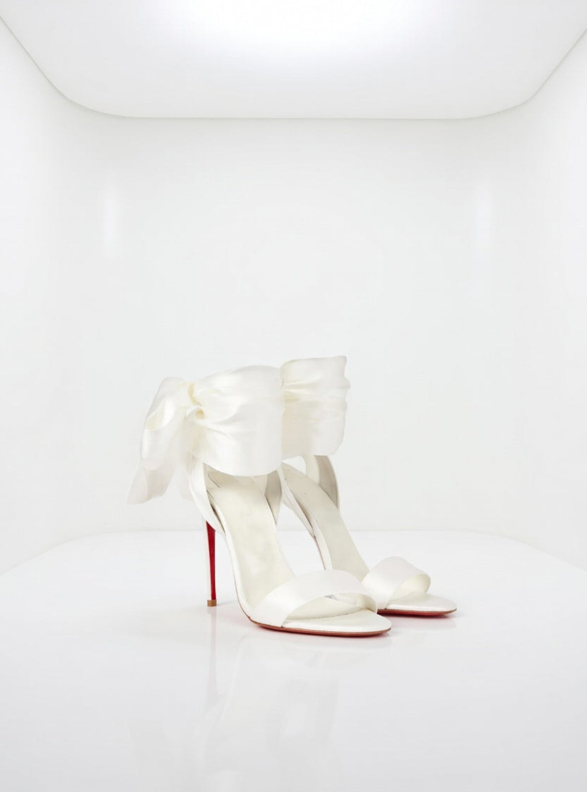 White high-heeled shoes with red soles on a white background