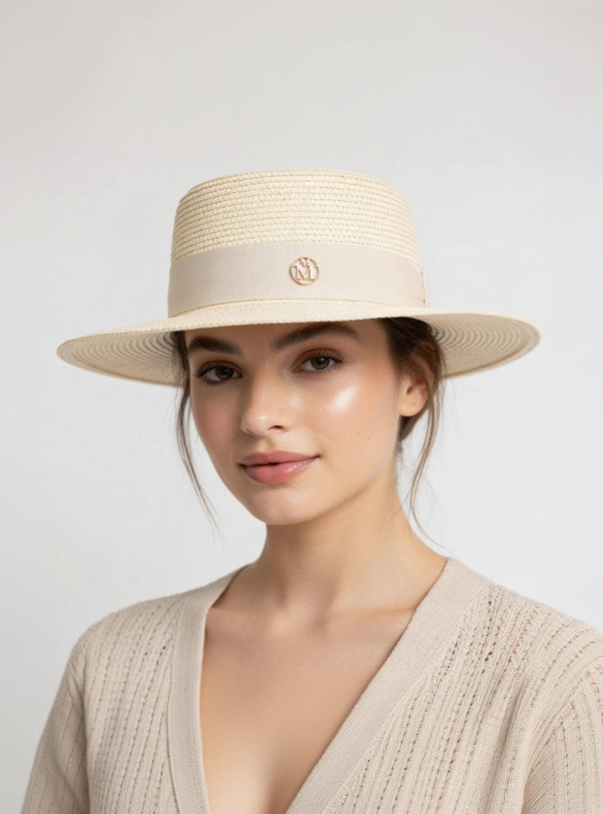Woman wearing a beige straw hat with a visible brand logo on a light gray background