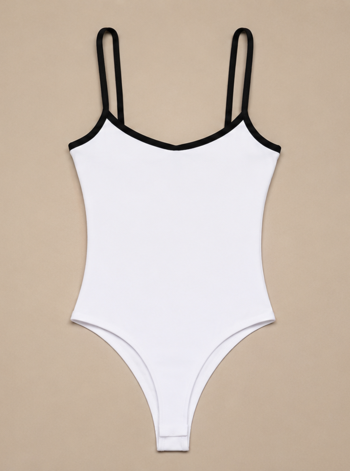 A white one-piece bodysuit with thin black shoulder straps and black trim along the neckline, displayed flat against a solid beige background.
