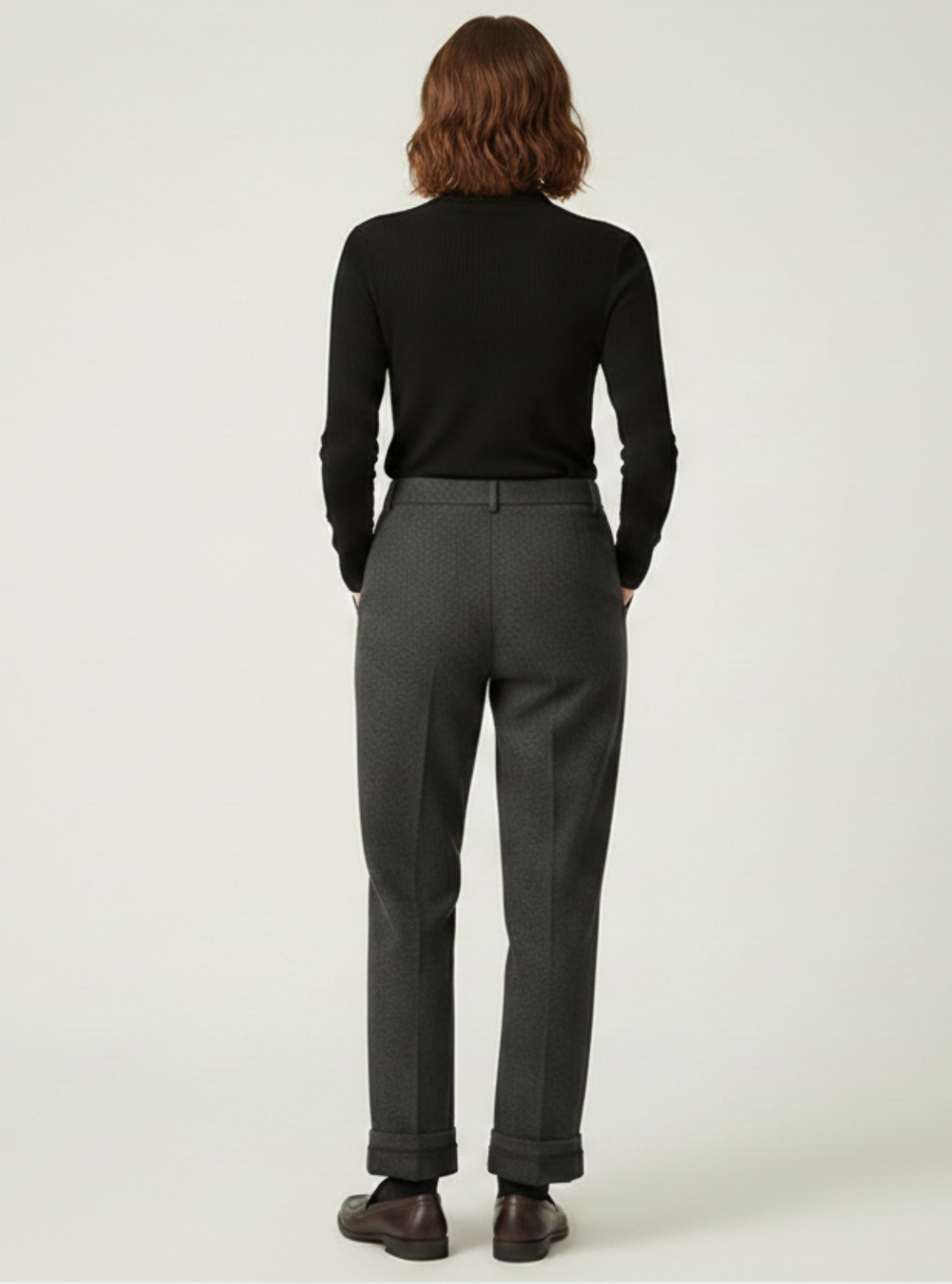 Person wearing a black shirt and gray pants against a white background
