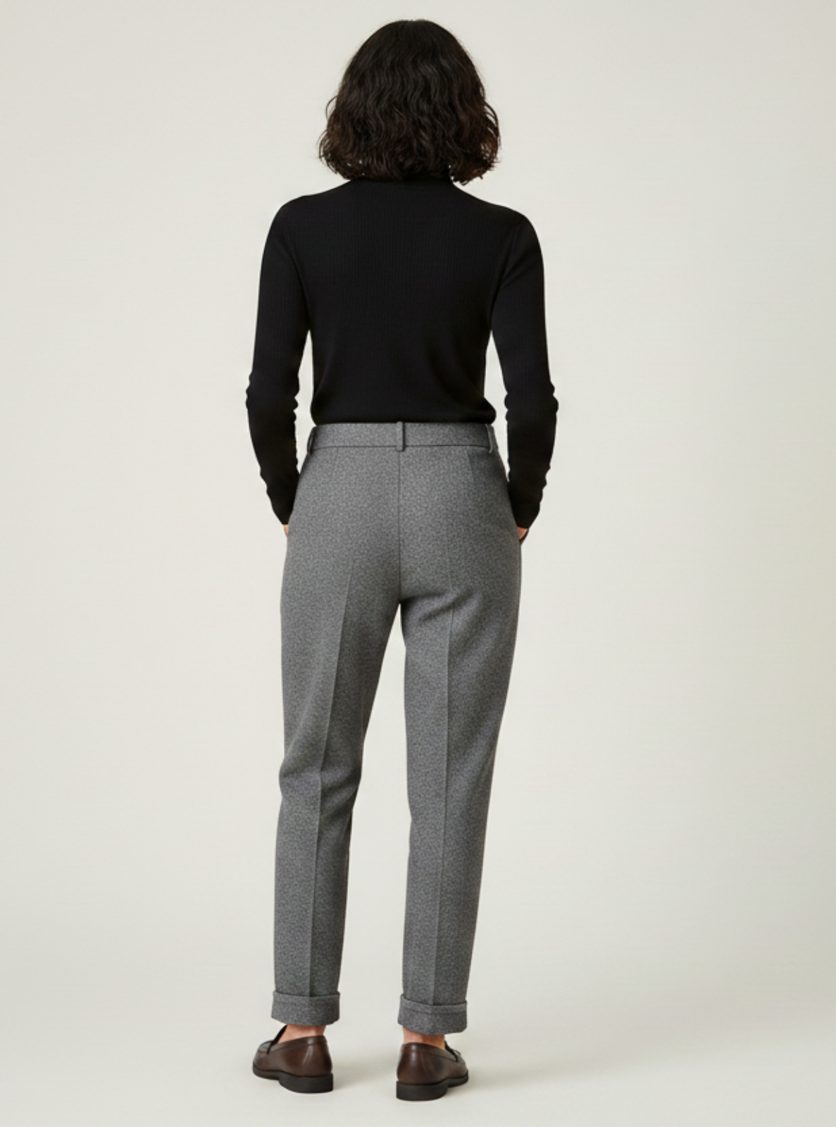 Person wearing gray pants and a black top on a white background