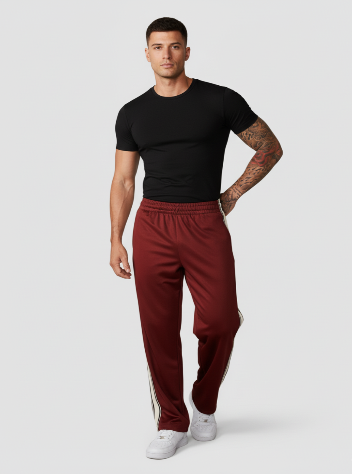 Man wearing a black t-shirt and red pants with white stripes on a white background