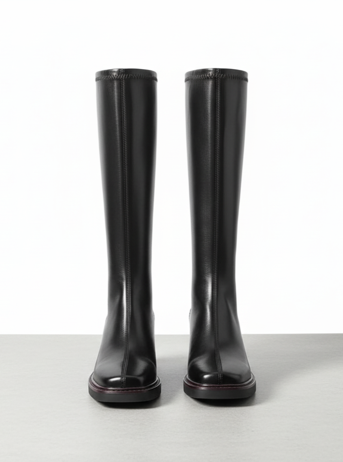Pair of black knee-high boots on a light gray background