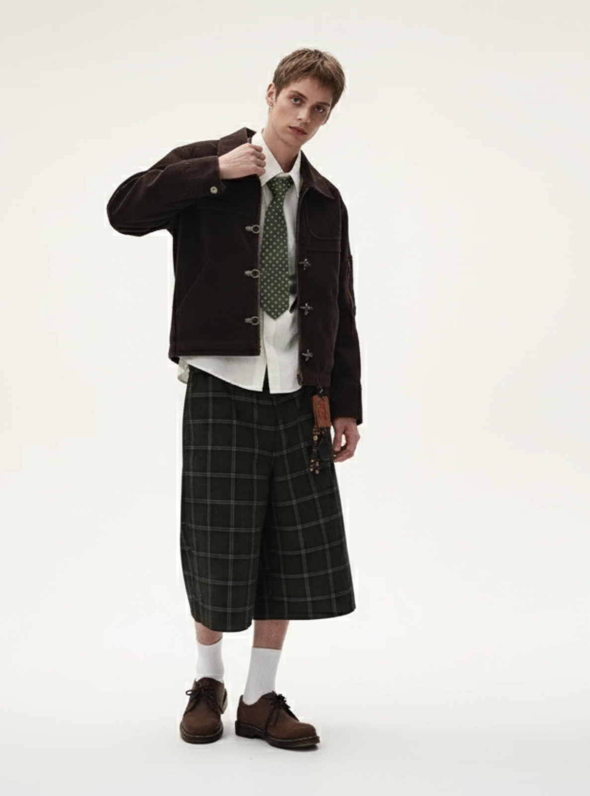 Person wearing a dark jacket, plaid skirt, and tie on a white background