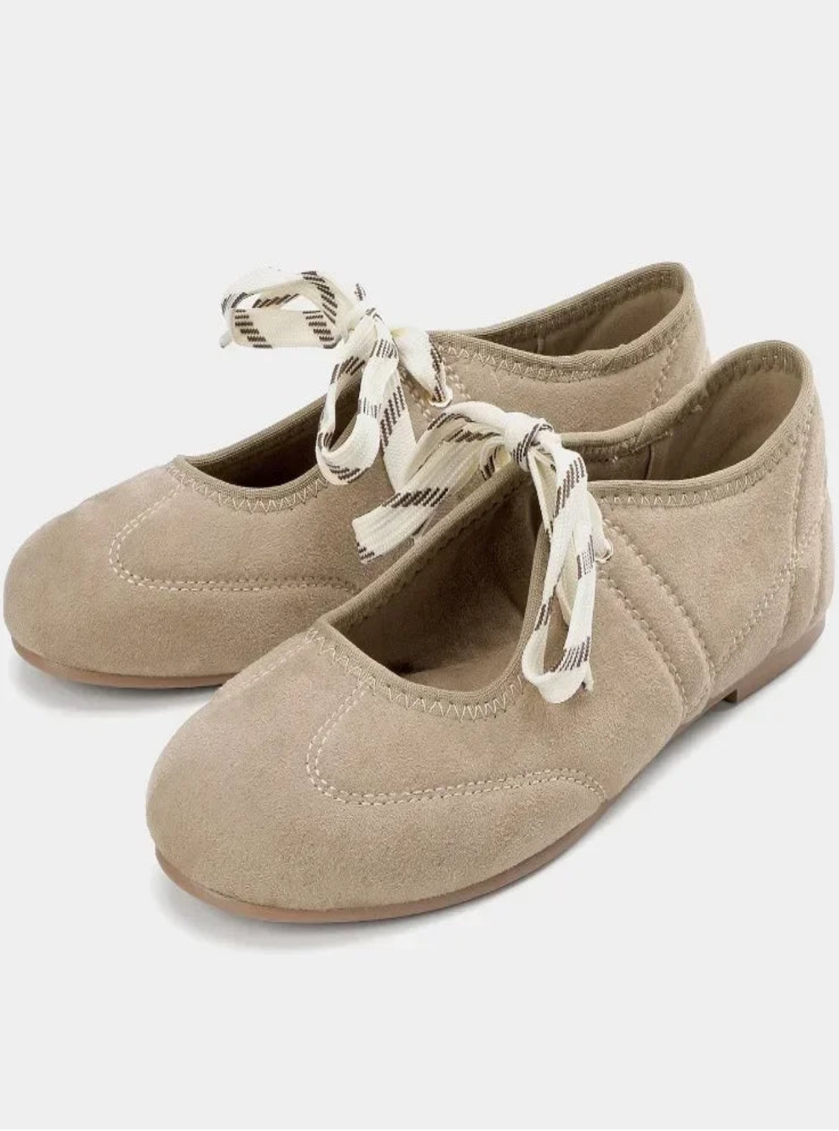 Pair of beige ballet flats with a ribbon on a white background