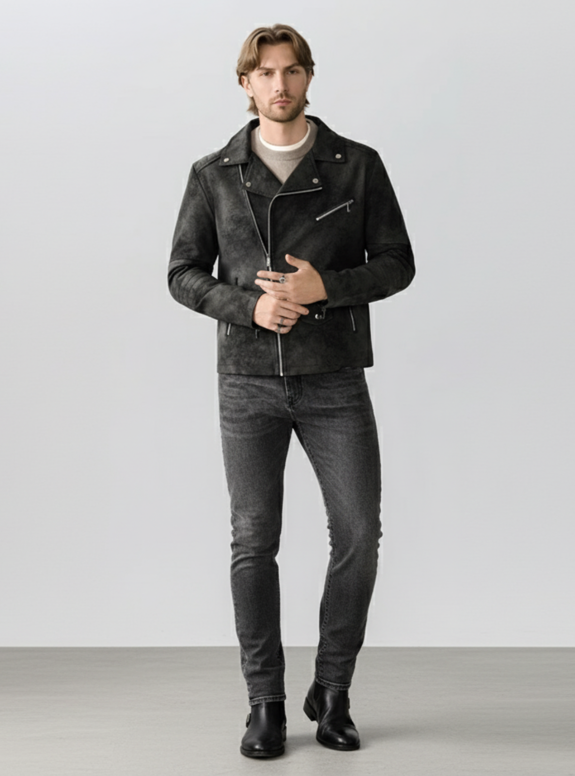 Man wearing a black leather jacket and jeans on a plain background