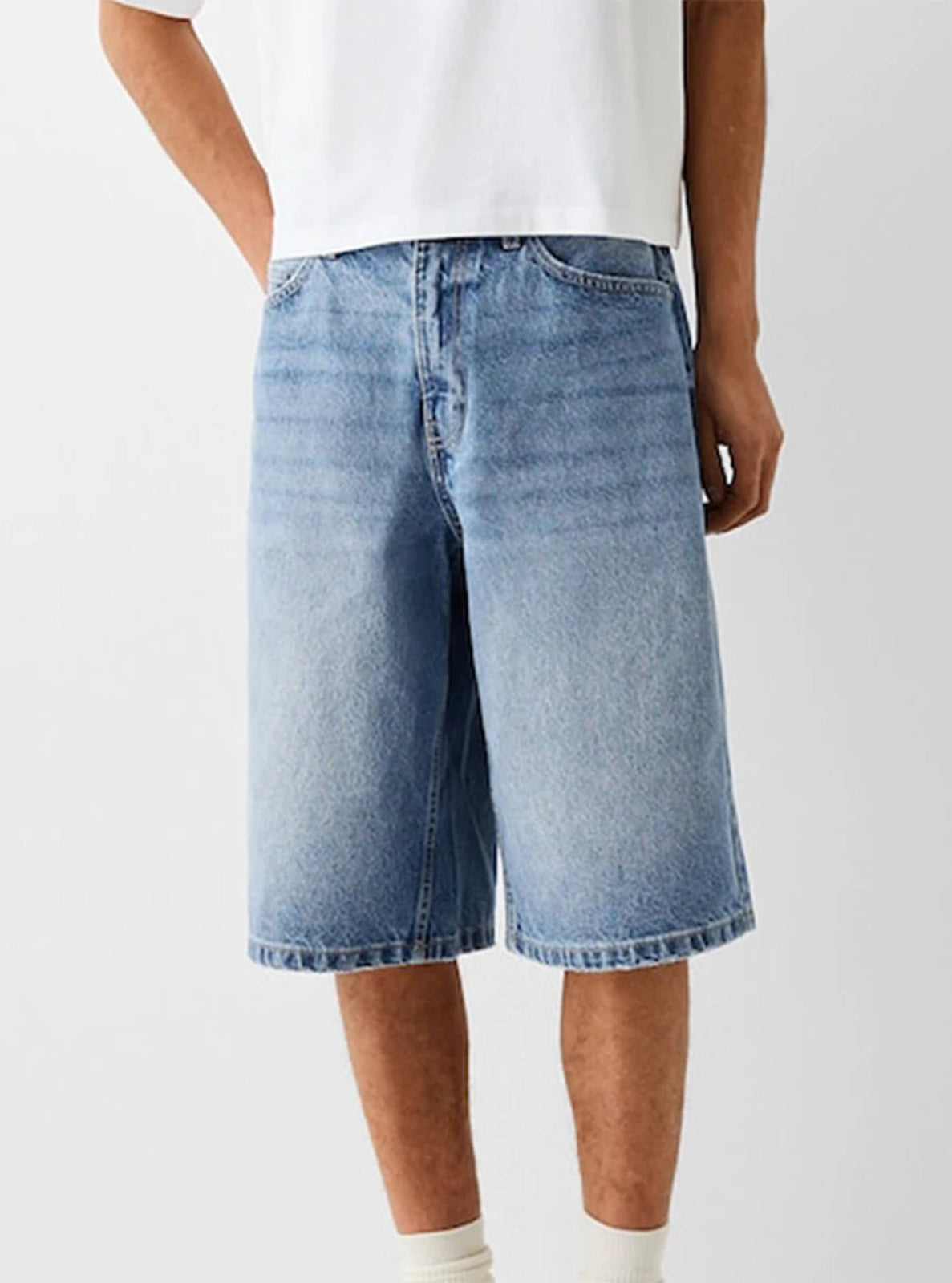 Person wearing light blue denim shorts on a white background