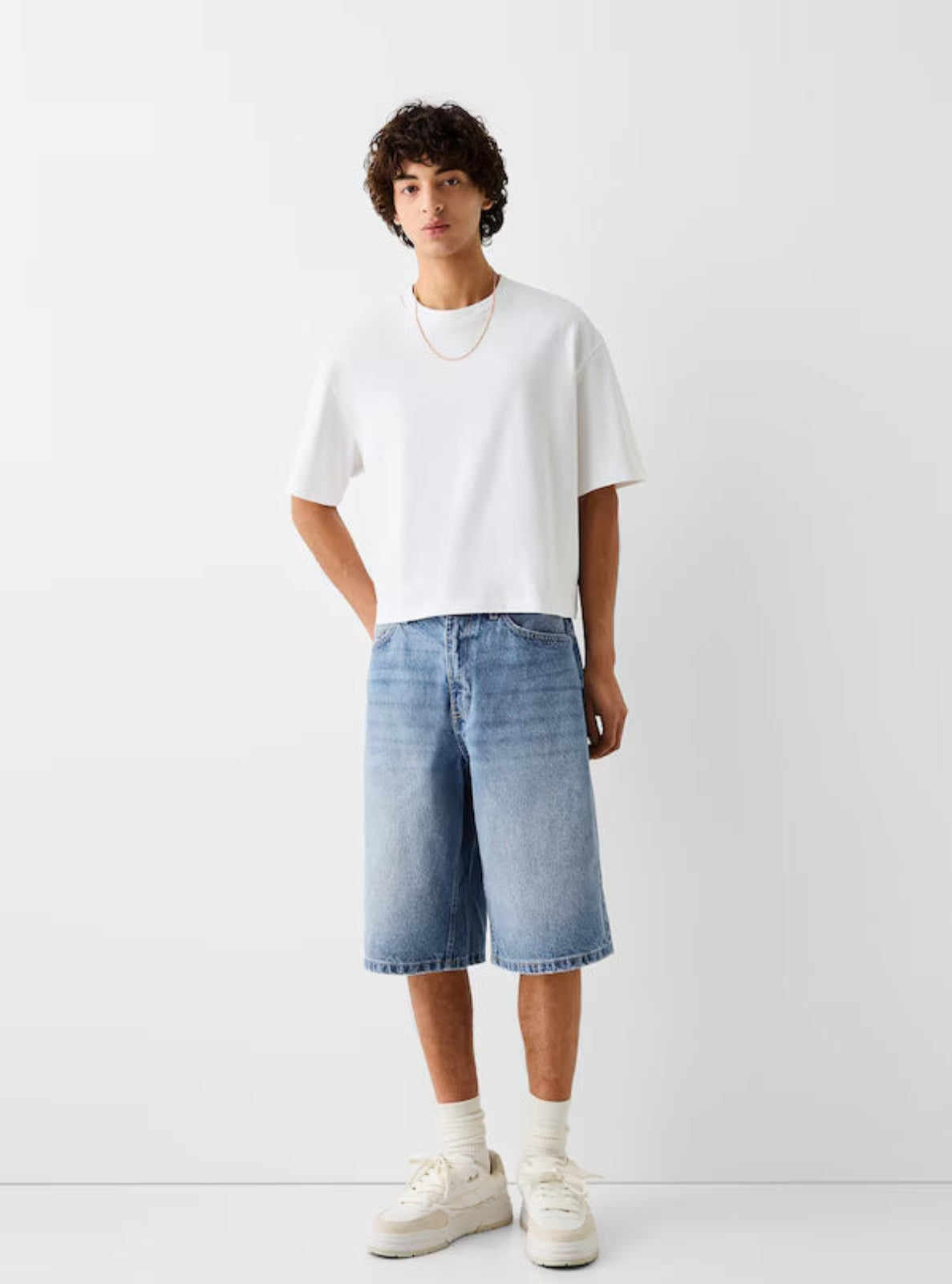Person wearing a white t-shirt and light blue denim shorts on a white background