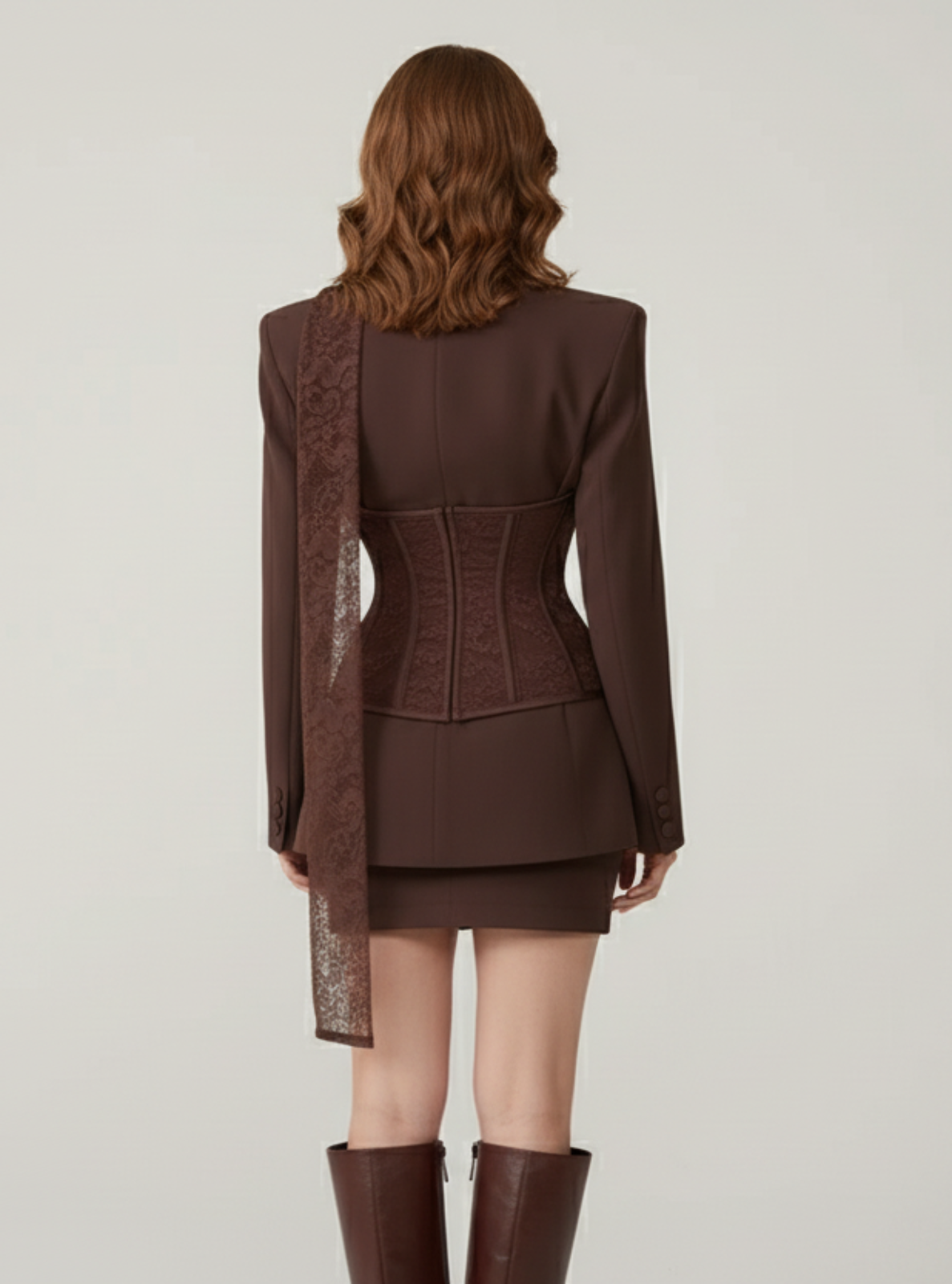 Brown suit with matching skirt and knee-high boots on a plain background