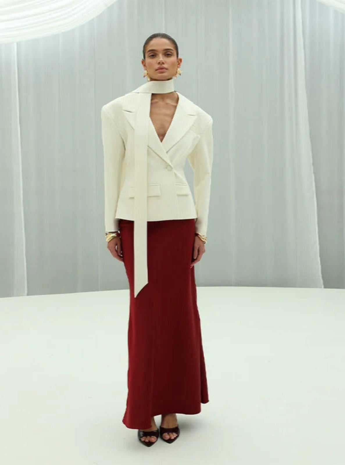 Woman wearing a white blazer and red skirt against a neutral background