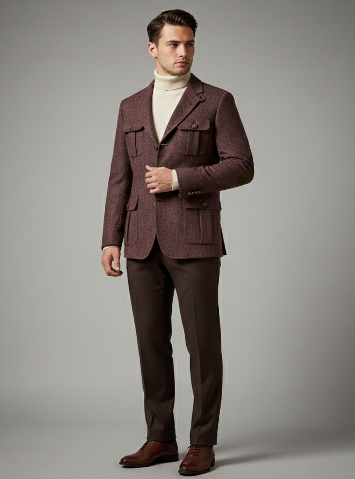 Man wearing a brown suit with a white turtleneck against a gray background