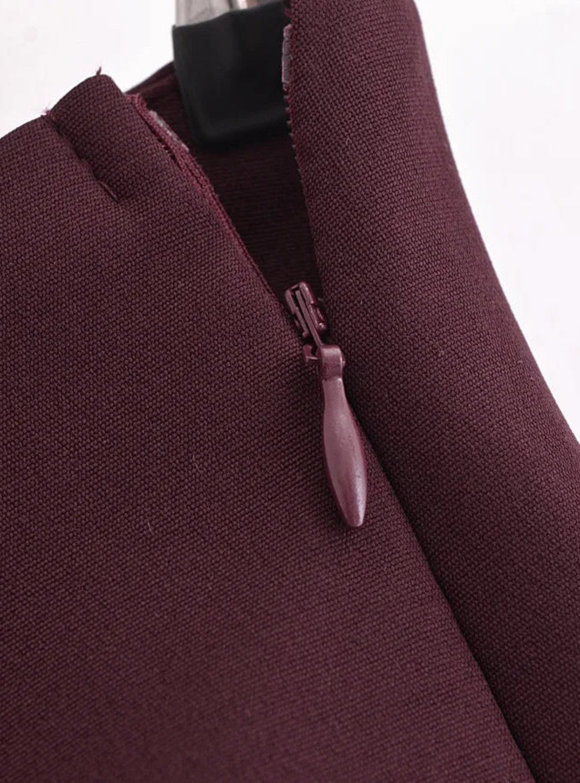 Close-up of a maroon garment with a zipper on a white background