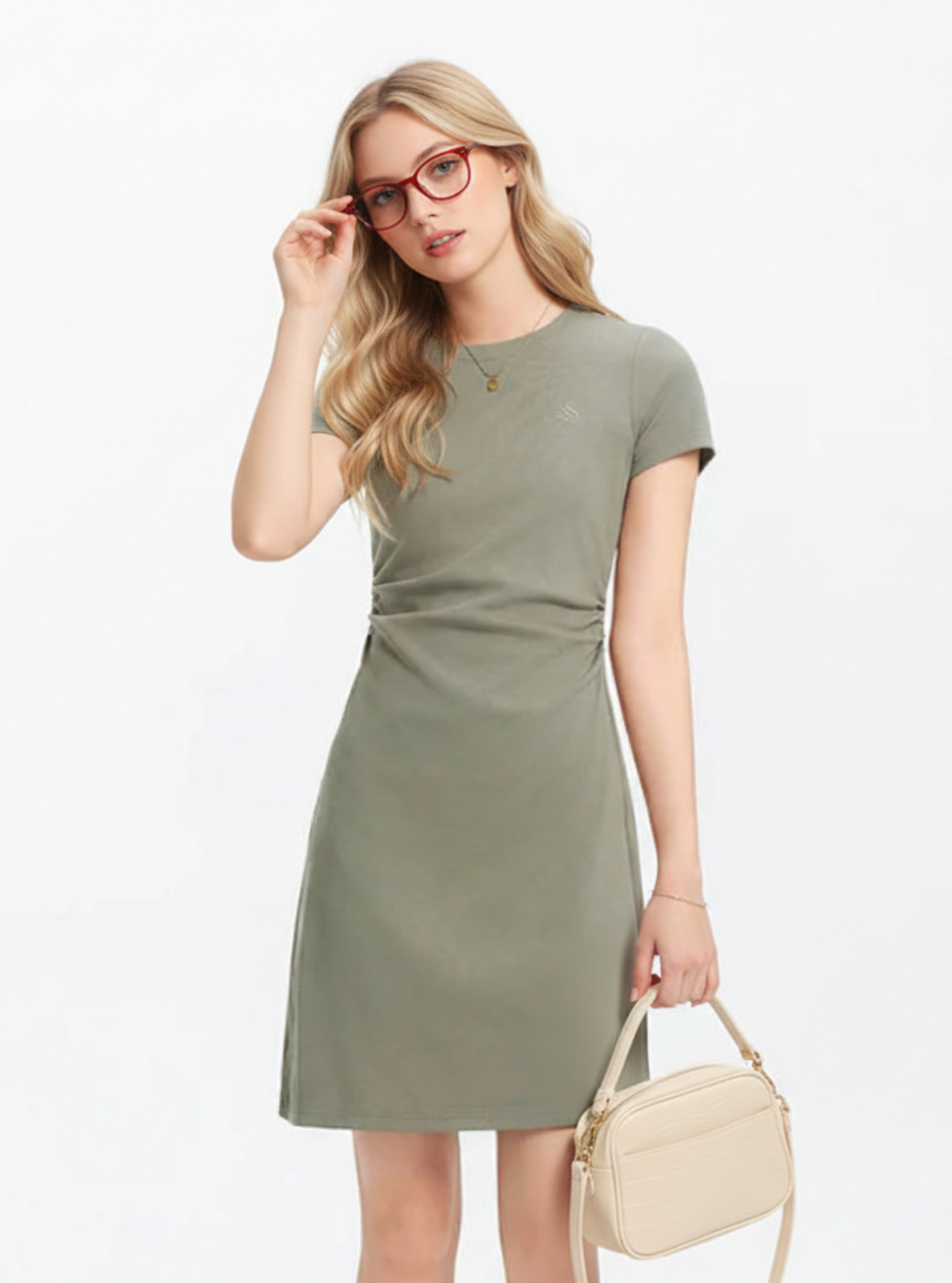 Woman wearing a green dress holding a beige handbag on a white background