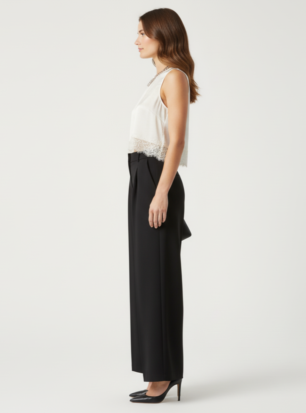 Woman wearing a white sleeveless top and black wide-leg pants on a white background