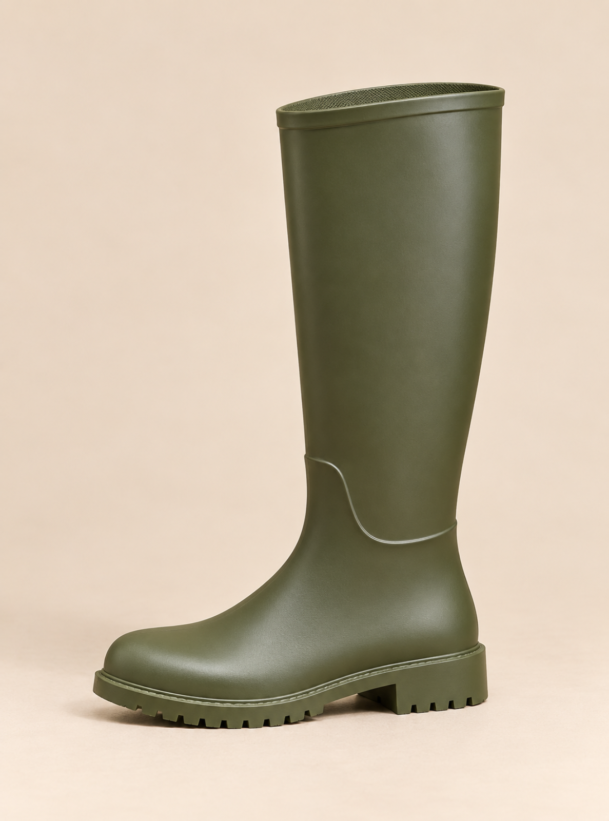 An olive green rubber rain boot with a low block heel and lug sole, shown from a side profile against a solid beige background.