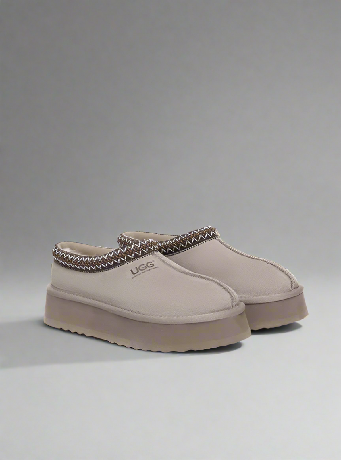 Beige UGG slippers on a gray background