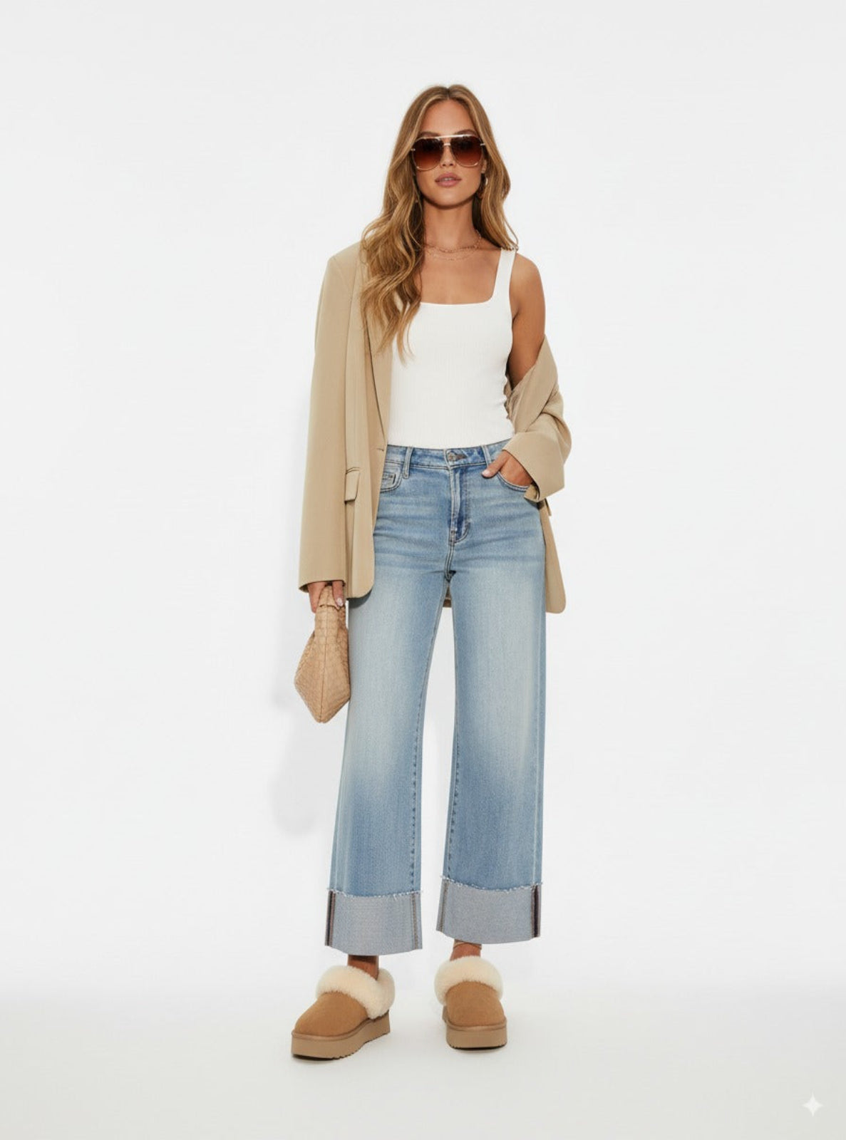Woman wearing a beige blazer, white top, light blue jeans, and brown shoes on a white background