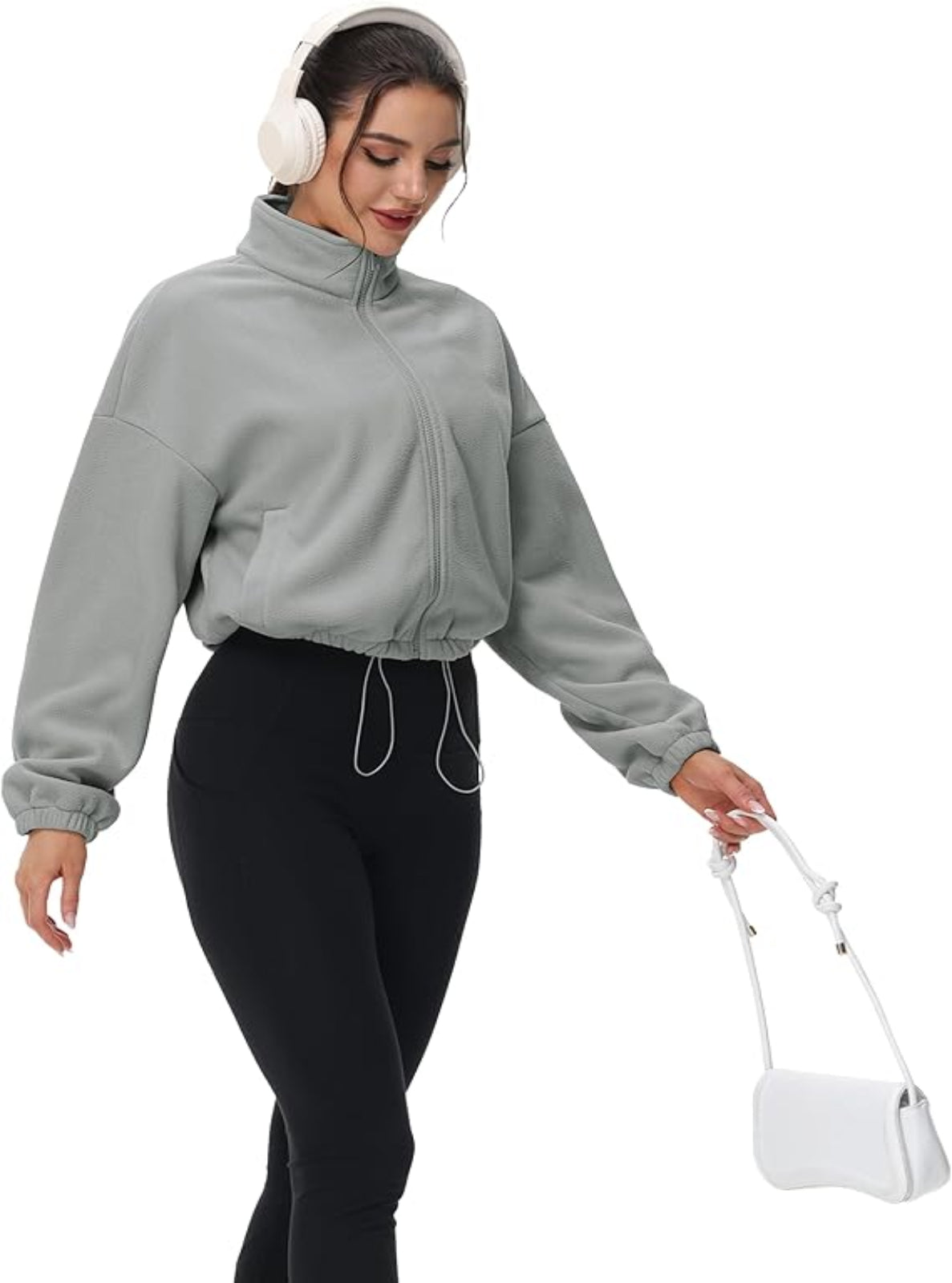 Woman wearing a gray jacket and black pants, holding a white bag on a white background
