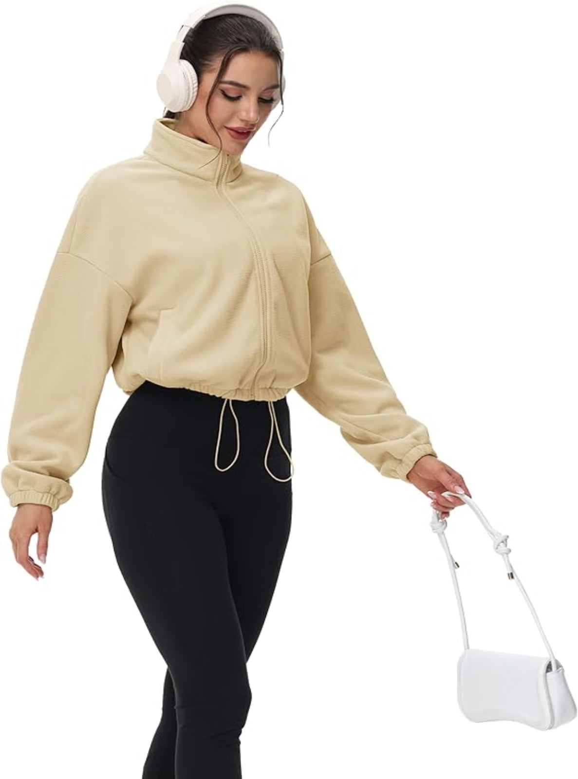 Woman wearing a beige jacket and black pants, holding a white bag on a white background