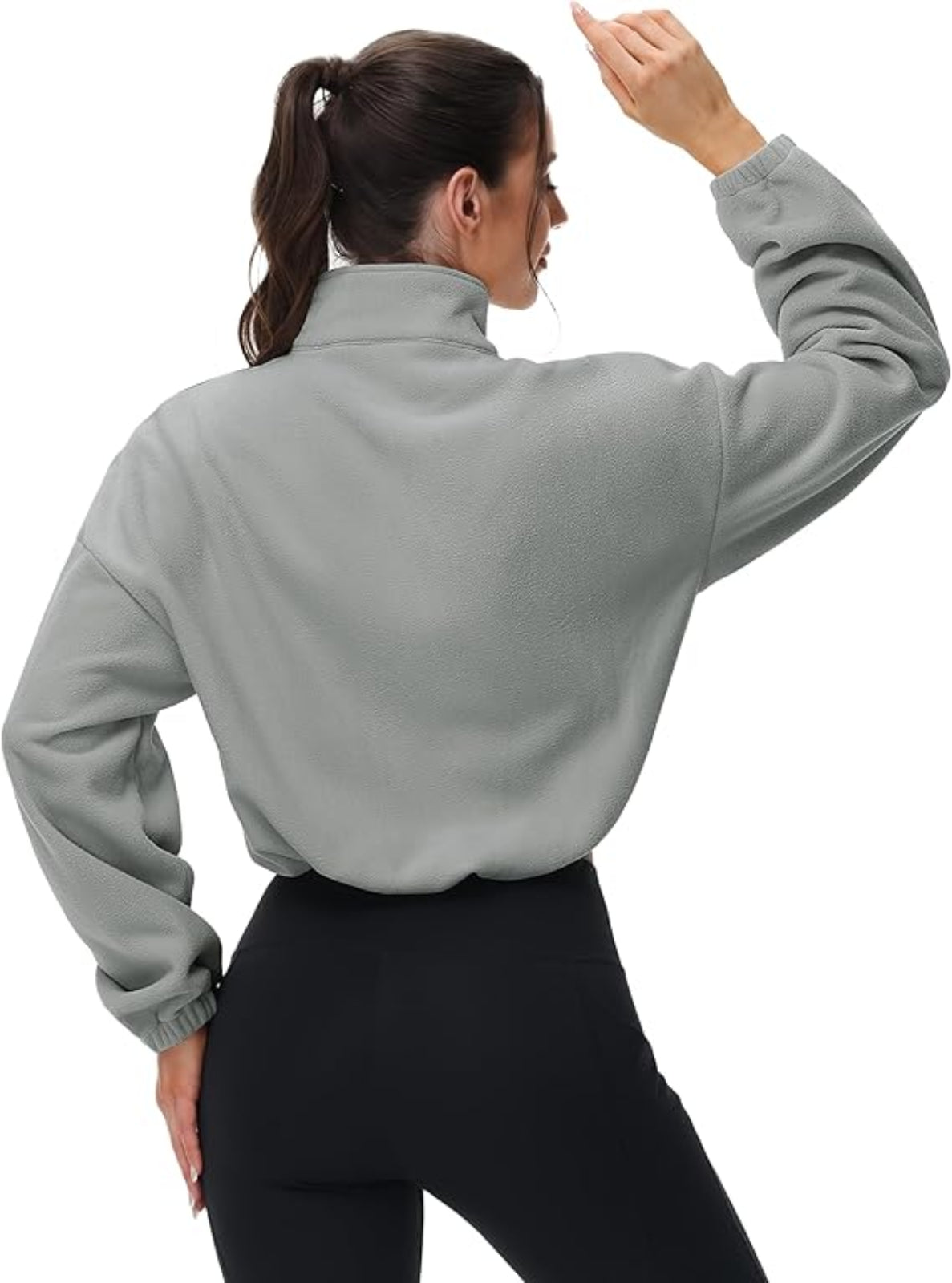 Person wearing a gray long-sleeve top and black pants on a white background