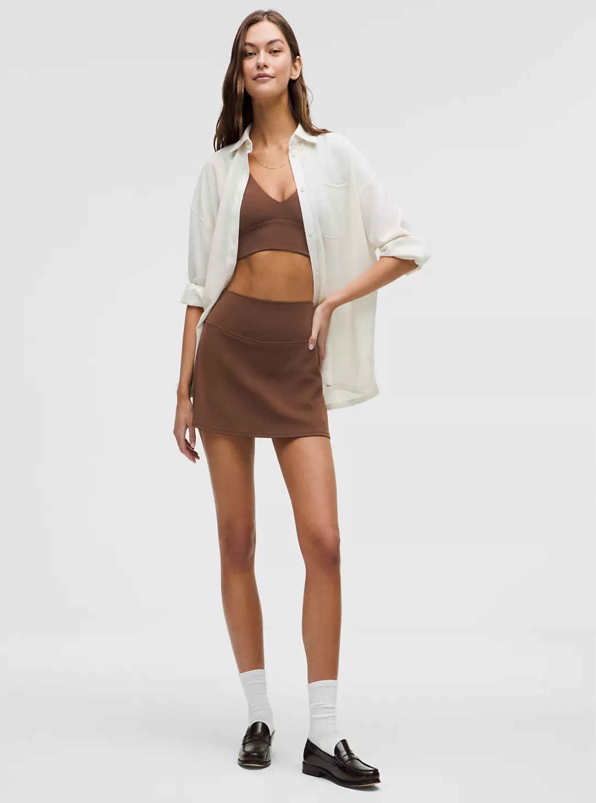 Woman wearing a white shirt, brown skirt, and brown top on a white background