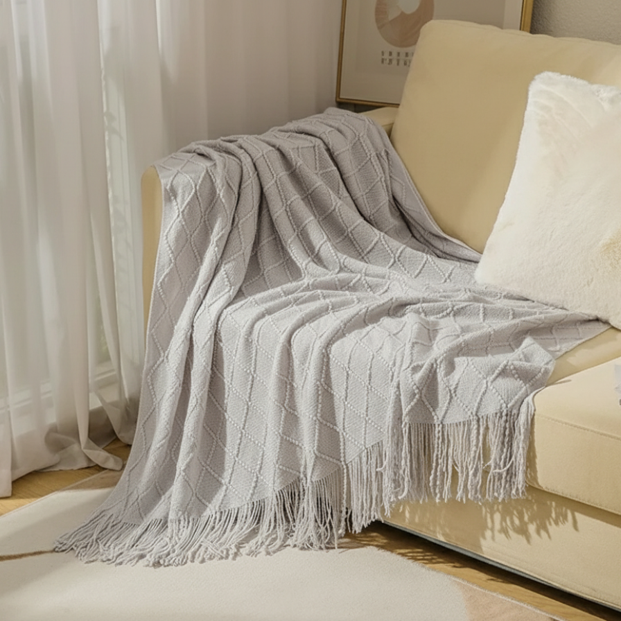 Gray textured throw blanket draped over a beige sofa with a white pillow.