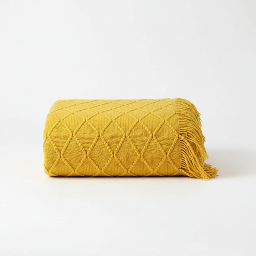 Yellow quilted blanket with fringes on a white background