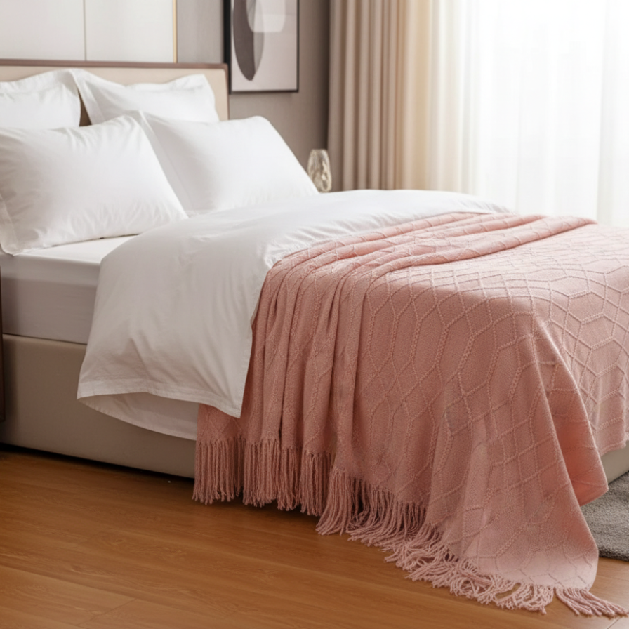 Bedroom with a bed featuring white bedding and a pink blanket, next to a wooden nightstand.