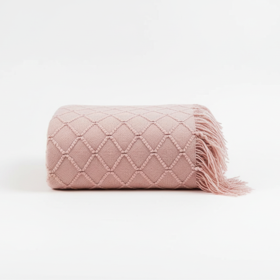 Pink quilted blanket with tassels on a white background