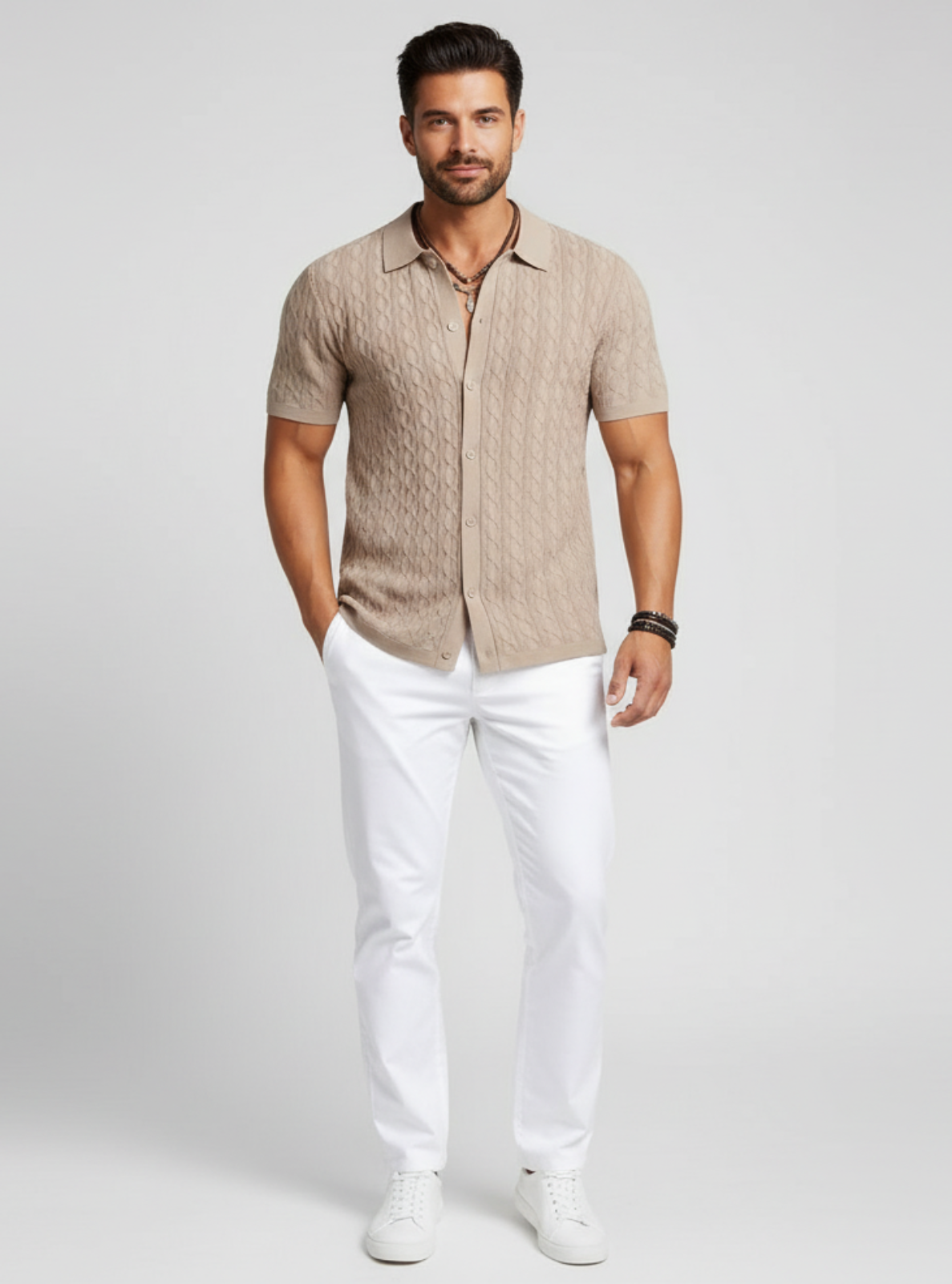 Man wearing a beige short-sleeve shirt and white pants on a light gray background