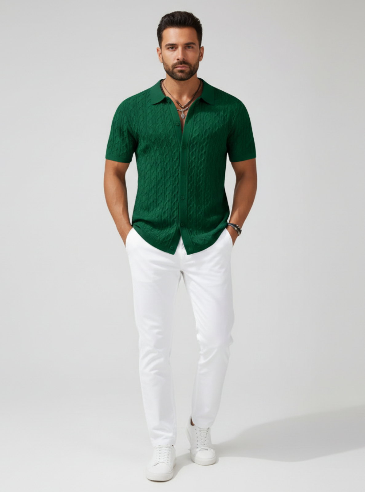 Man wearing a green patterned shirt and white pants on a gray background