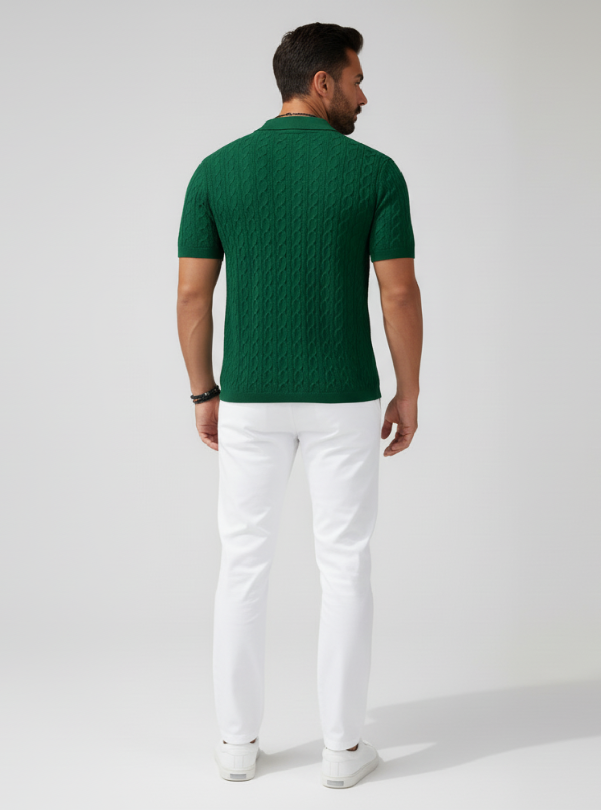 Man wearing a green patterned shirt and white pants on a gray background