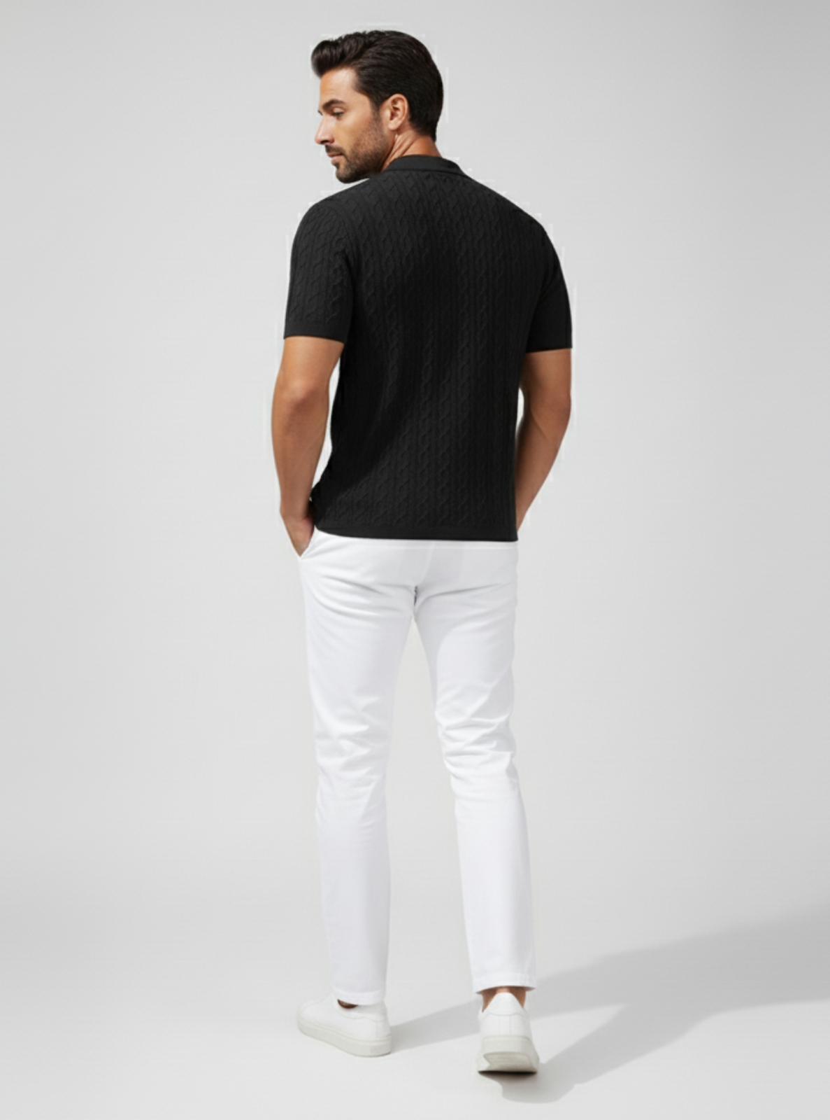 Man wearing a black shirt and white pants on a light gray background