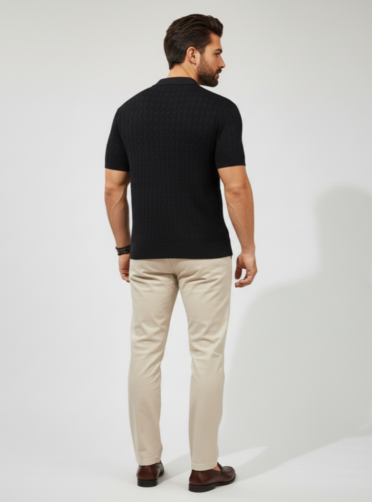 Man wearing a black t-shirt and beige pants on a white background