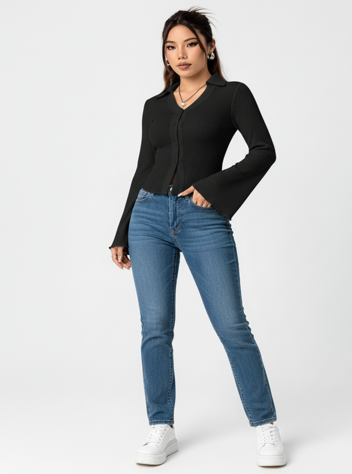 Woman wearing a black long-sleeve top and blue jeans on a white background