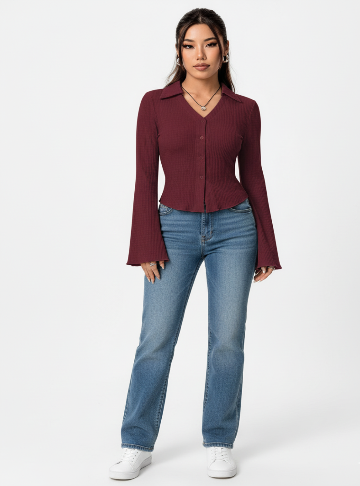 Woman wearing a burgundy blouse and blue jeans on a white background