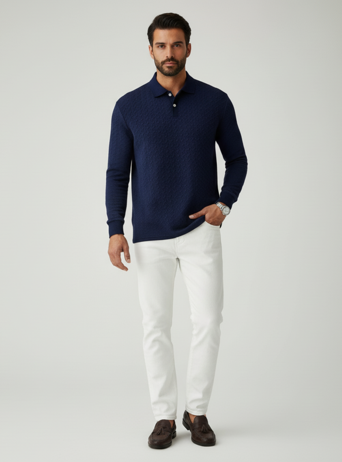 Man wearing a navy long-sleeve shirt and white pants on a light gray background