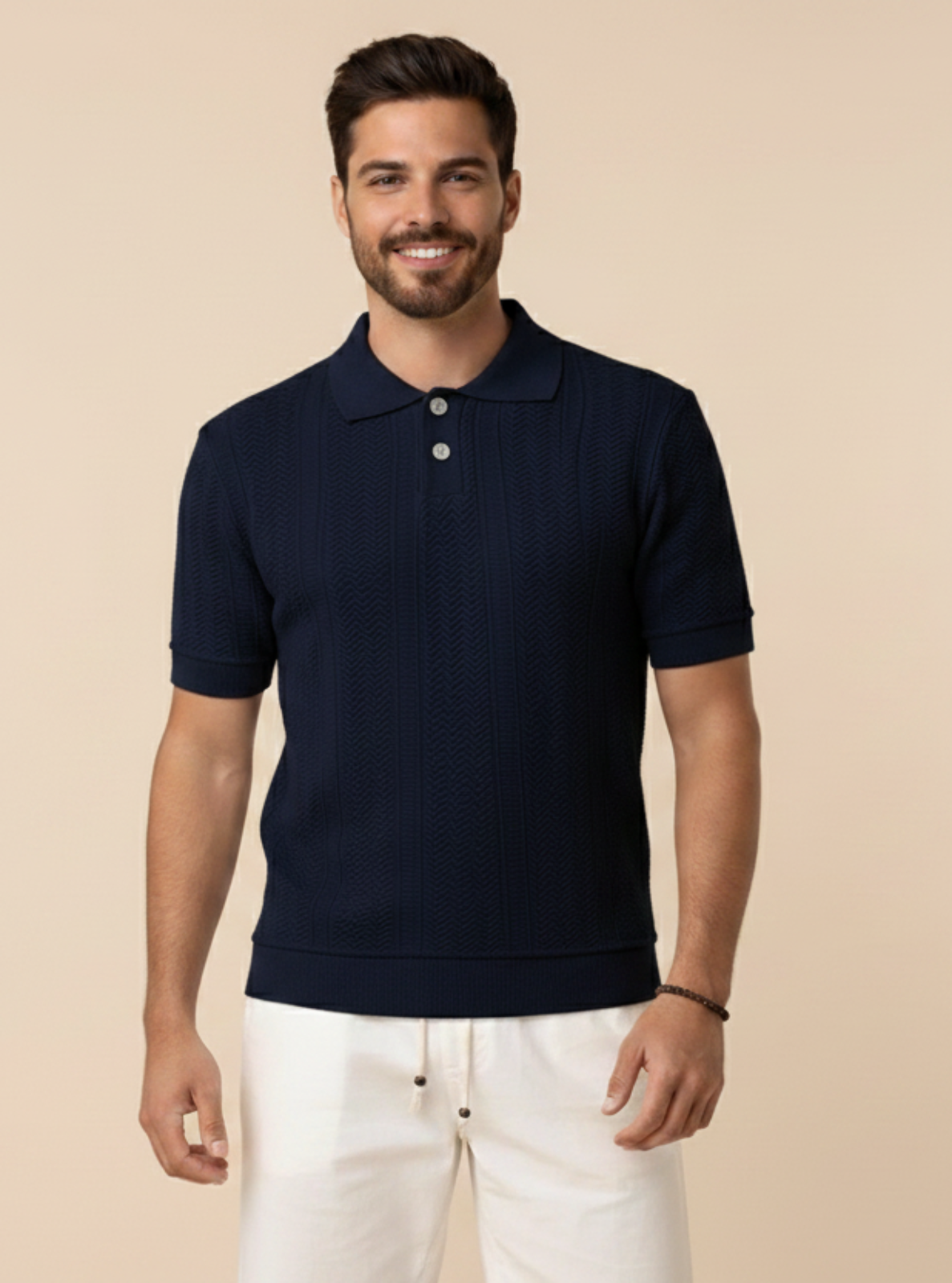 Man wearing a navy polo shirt and white pants on a beige background