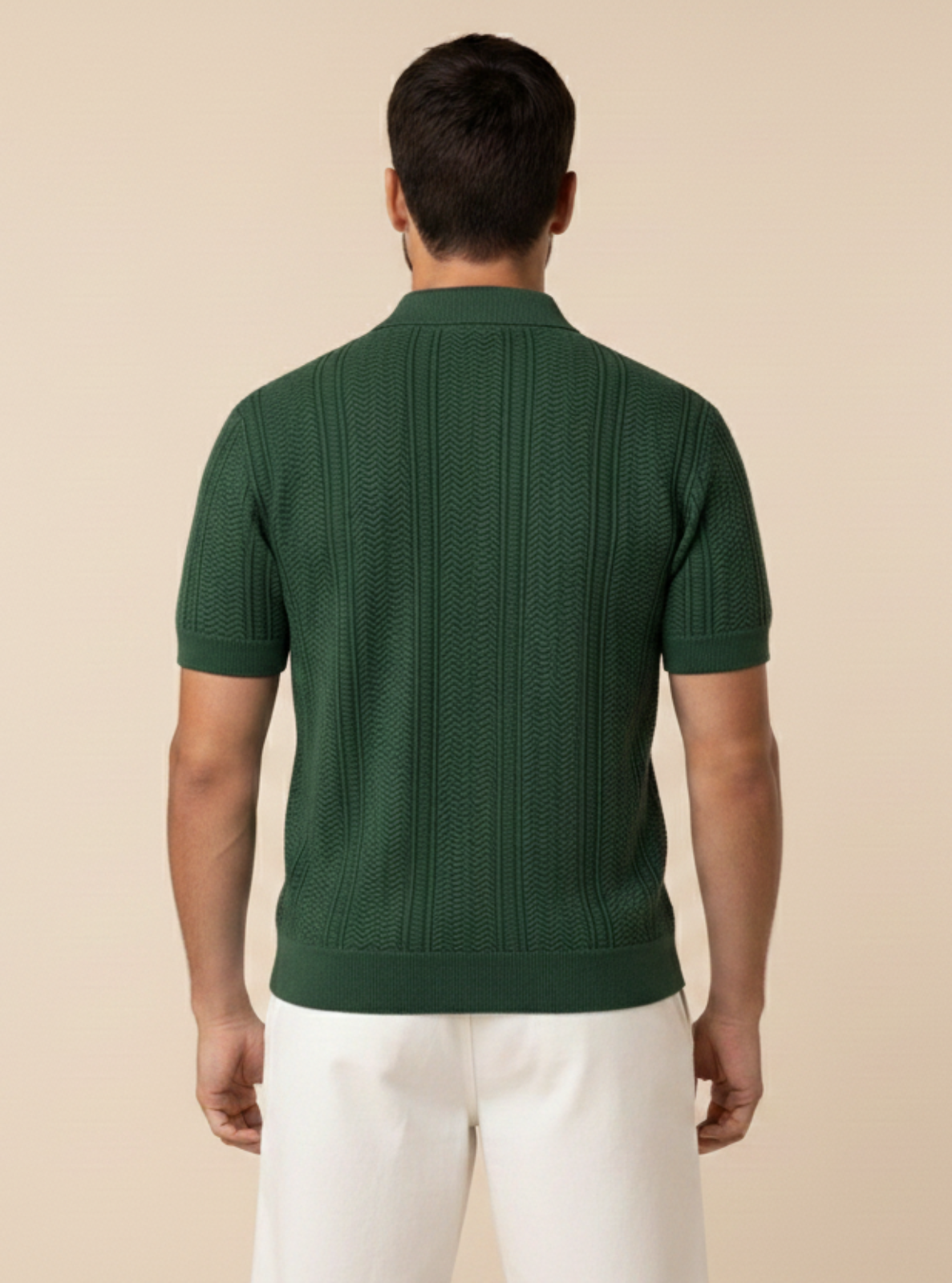 Man wearing a green ribbed sweater and white pants on a beige background