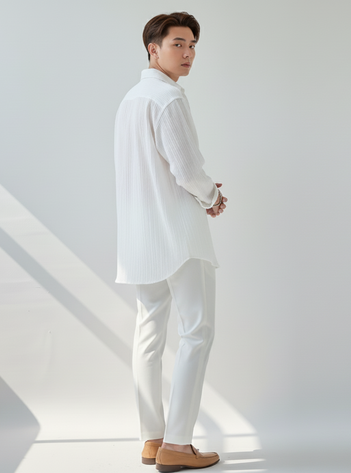 Man wearing a white outfit standing against a light gray background