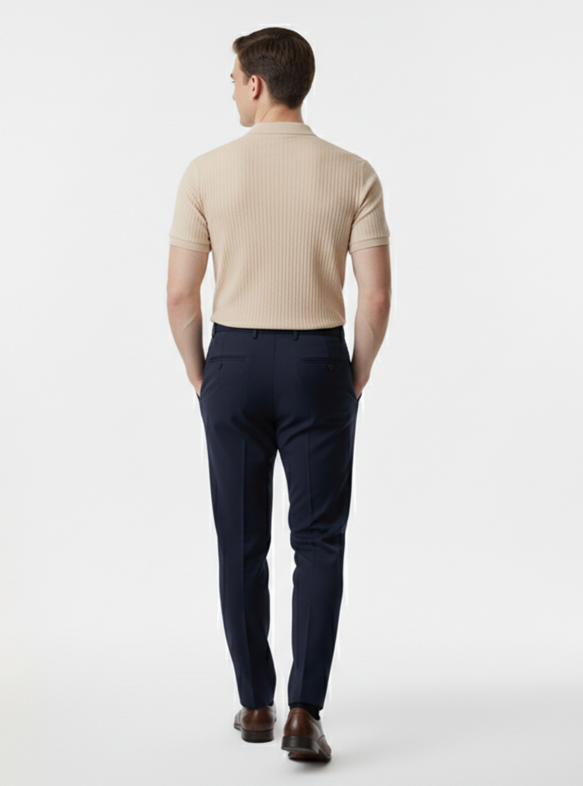 Man wearing a beige sweater and navy pants on a white background