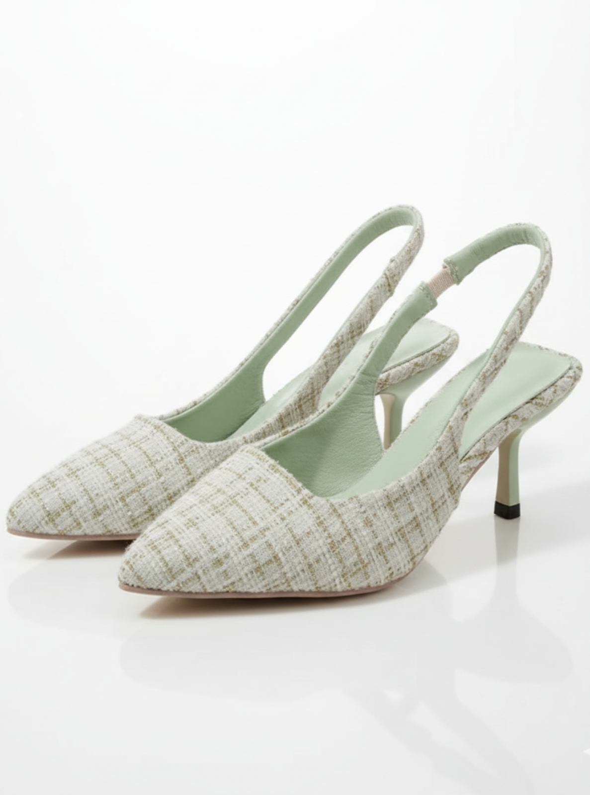 Pair of light green pointed-toe slingback heels on a white background