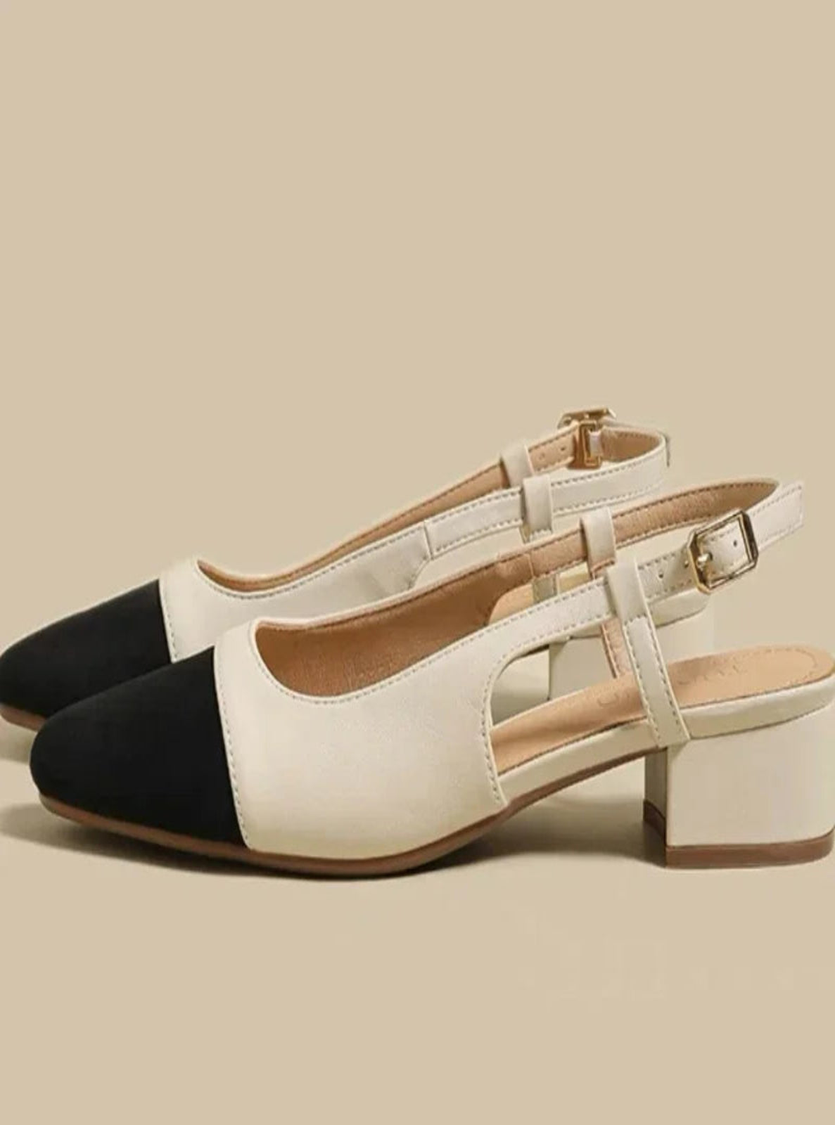 Pair of black and white shoes on a beige background