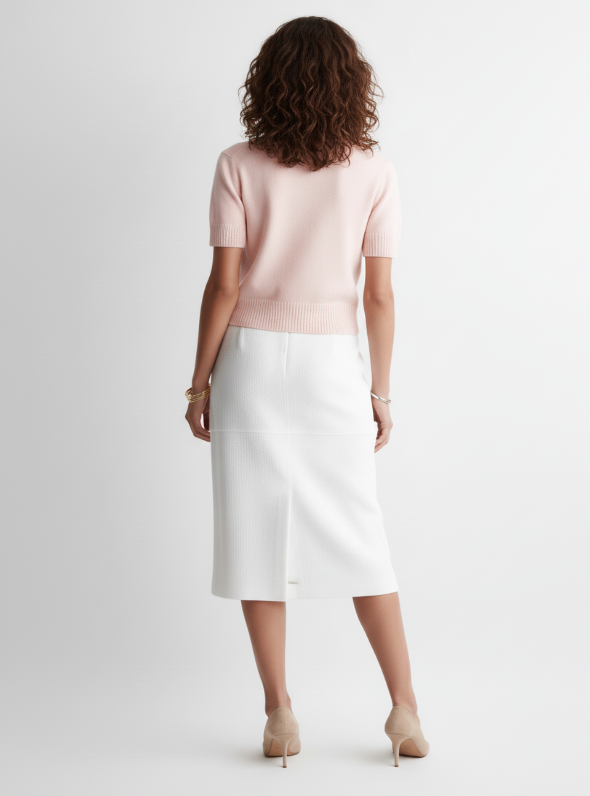 Woman wearing a light pink top and white skirt on a plain background