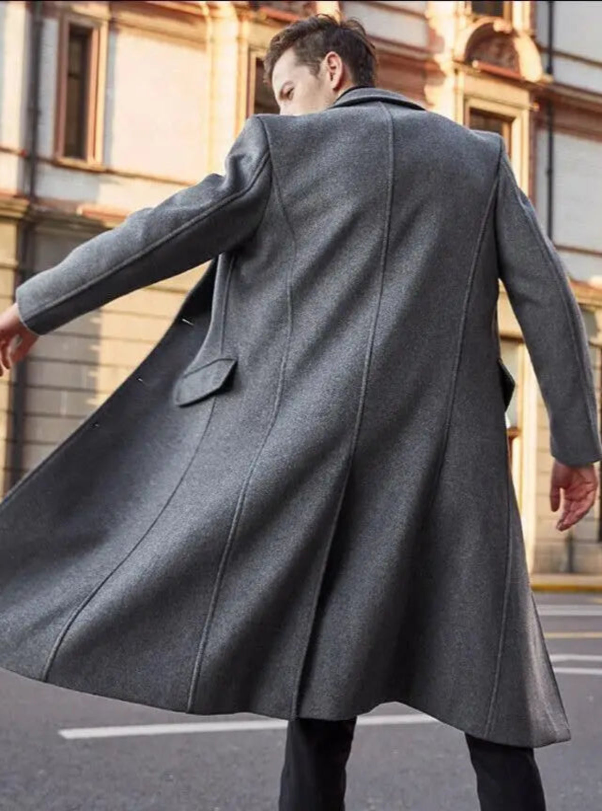 Man wearing a long gray coat walking on a city street.