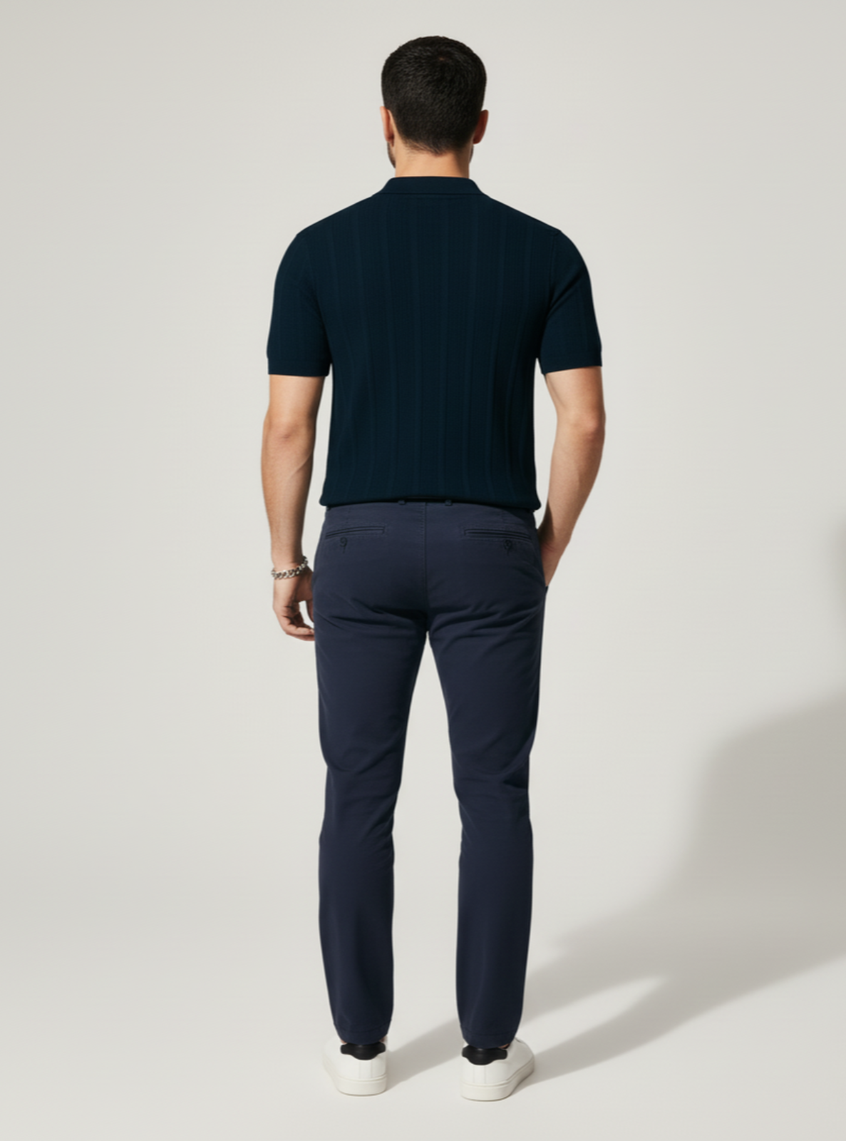 Man wearing a dark blue polo shirt and pants on a white background