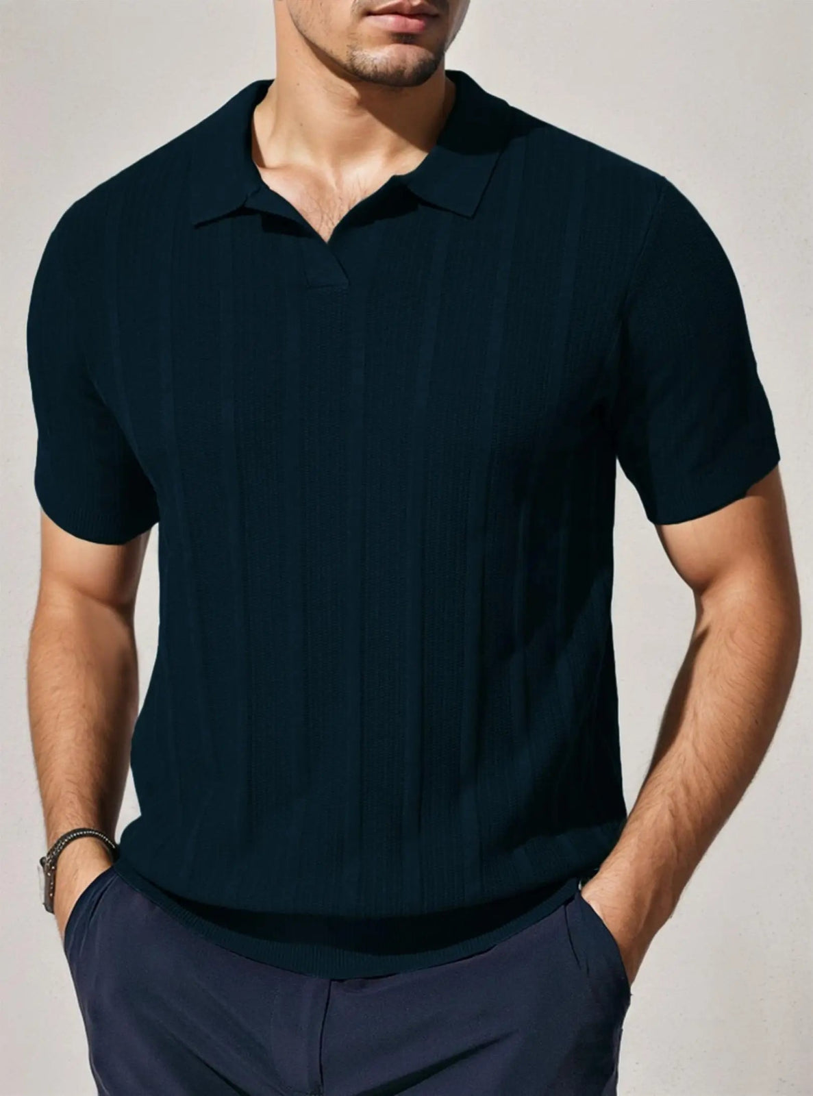 Man wearing a dark blue polo shirt against a plain background