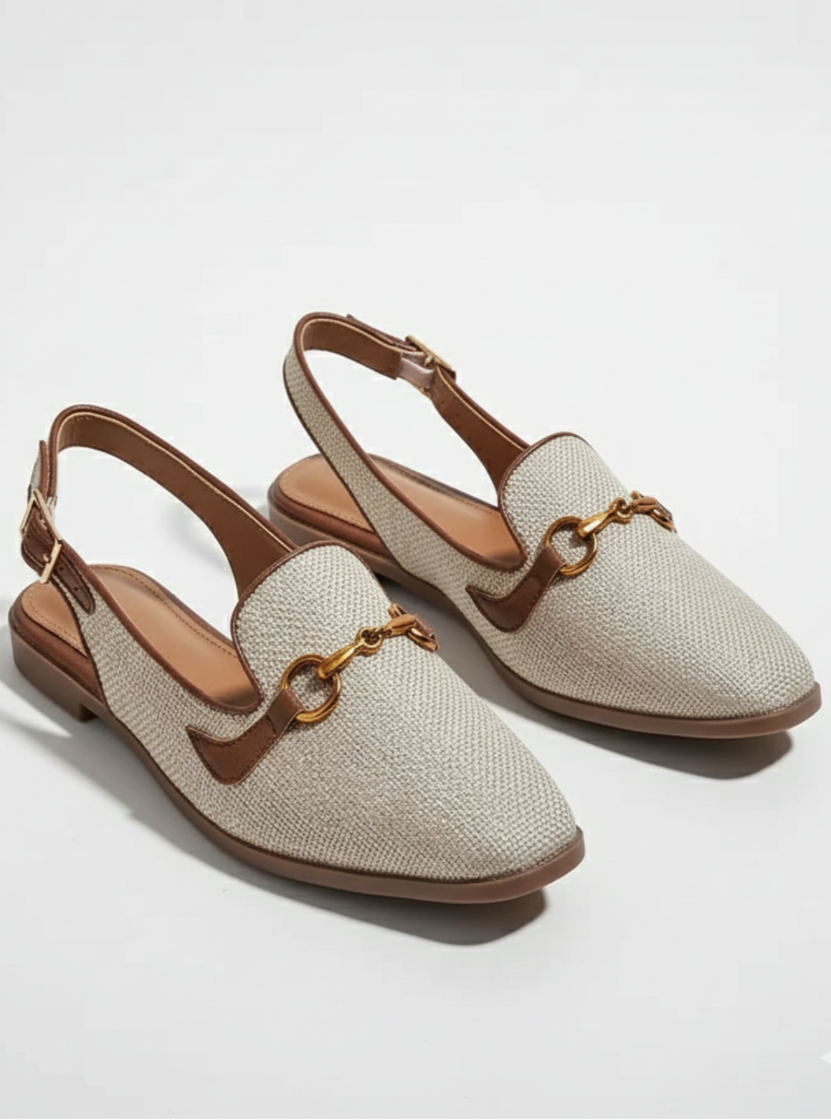 Pair of beige slingback shoes with brown accents on a light gray background